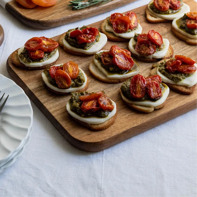 Image of roasted tomato, mozzarella and pesto bites on wooden board