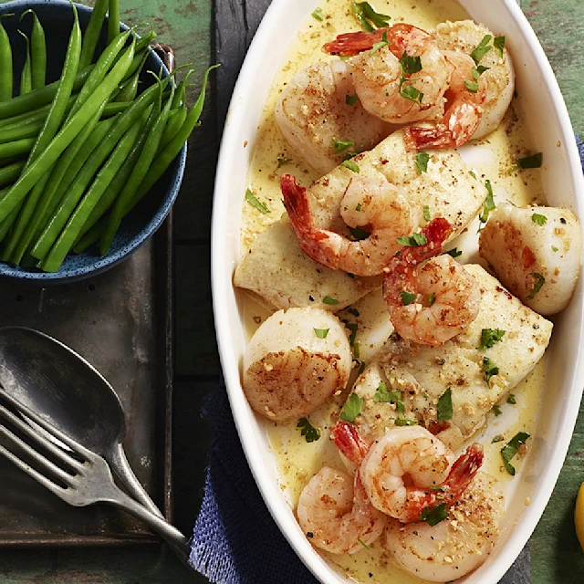 Aerial view of a plate of a provencal seafoods bake with lemon wedges on the side