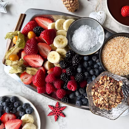A festive tray of cut fruit, nuts and fondue