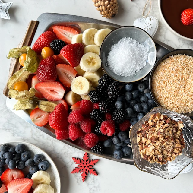 A festive tray of cut fruit, nuts and fondue