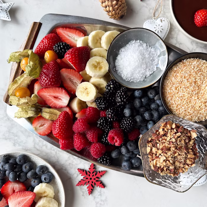 A festive tray of cut fruit, nuts and fondue