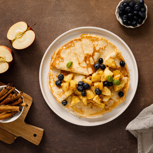 Aerial view of crepe cake topped with blueberries, apples and cinnamon