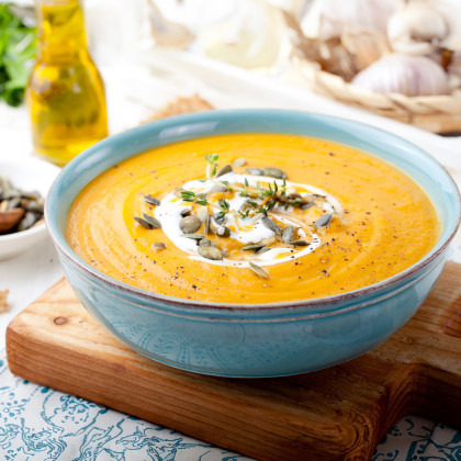 A bowl of roasted butternut squash soup, garnished with cream and herbs
