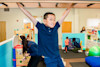 child in playground hanging from monkey bars smiling