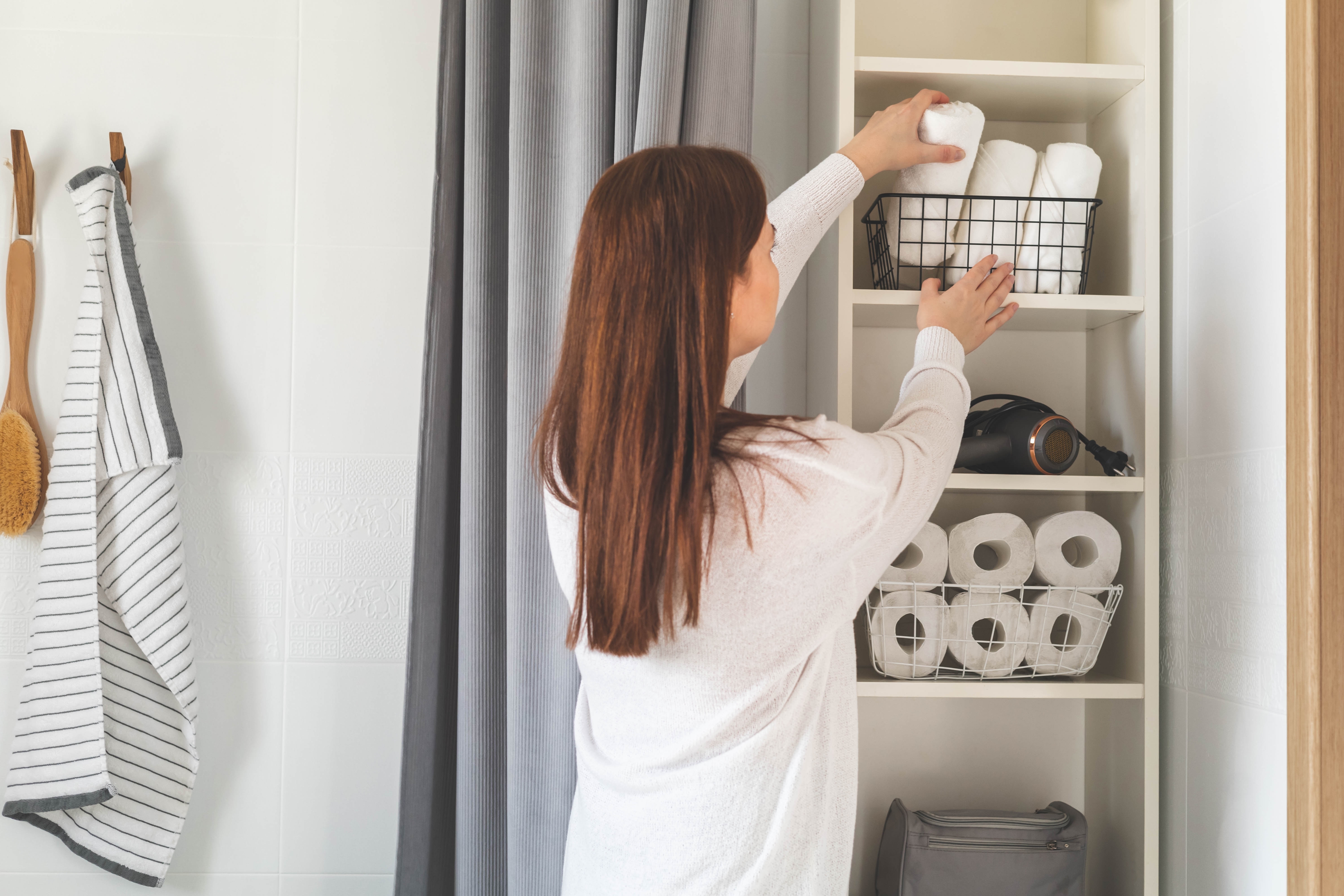 A woman placing paper towels in a closet