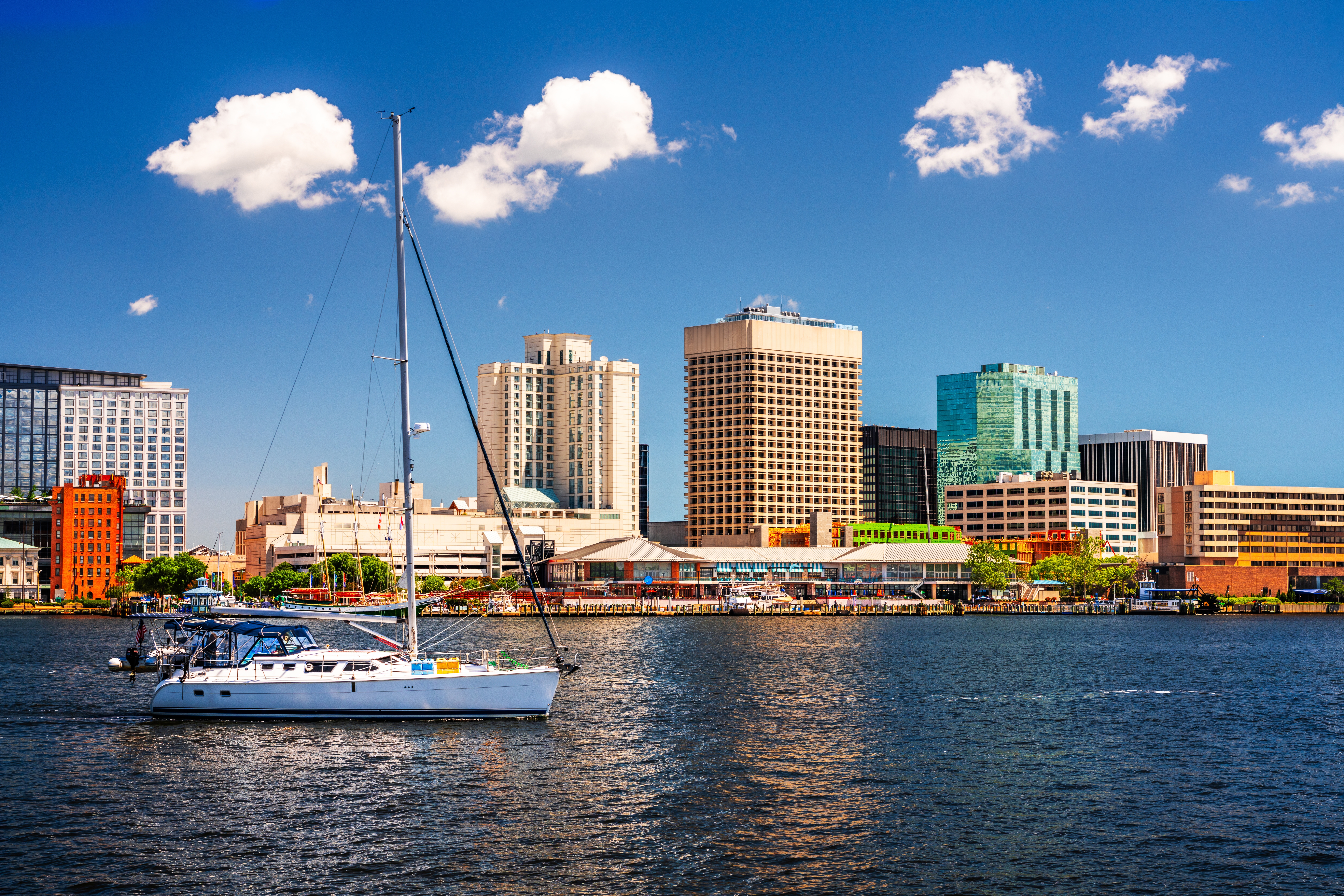 Skyline view of Chesapeake, VA with a boat in the water in the foreground and skyscrapers in the background