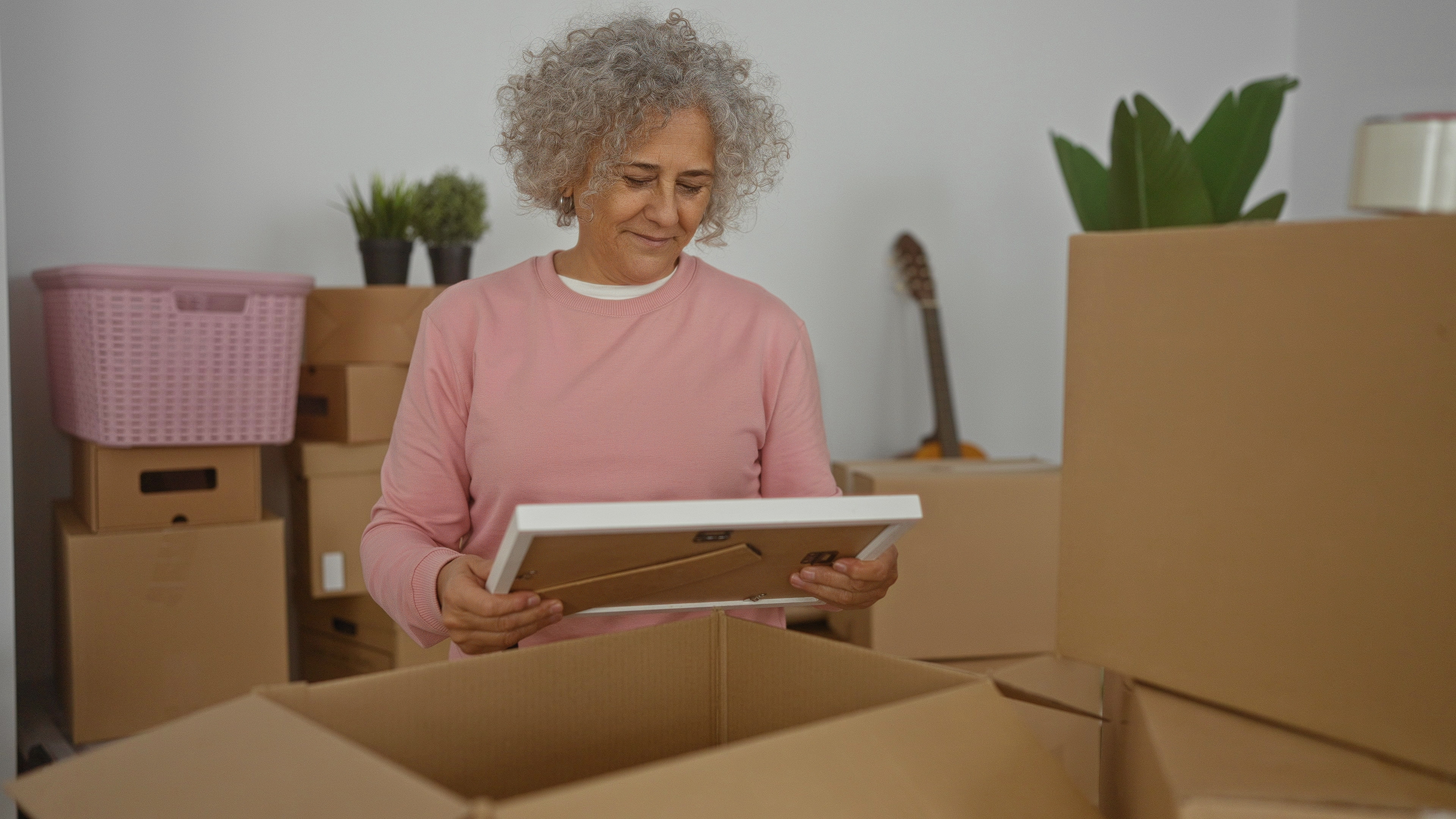 A woman looking at a photo surrounded by boxes