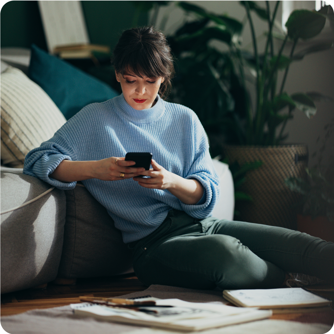Femme assise sur son téléphone dans son salon
