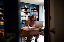 Jeune femme concentrée planifiant son lump sum, entre réflexion, notes et ordi dans un bureau en somme.