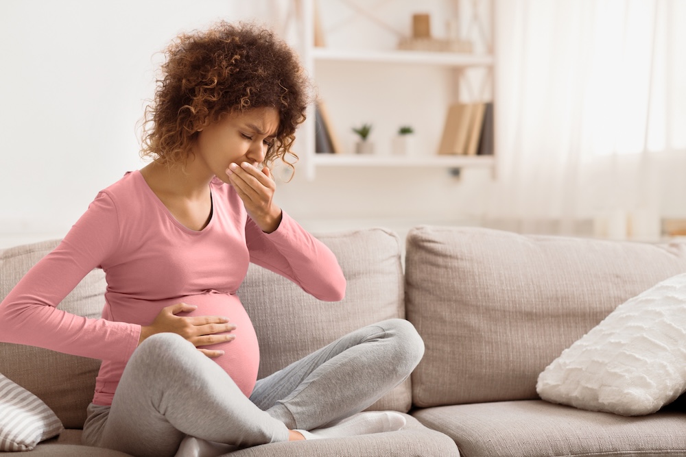 Pregnant woman on couch experiencing mouth discomfort