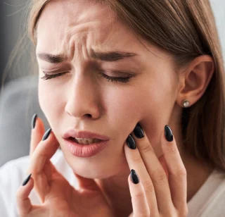 A person experiencing tooth pain possibly due to a cavity or tooth decay | Crest