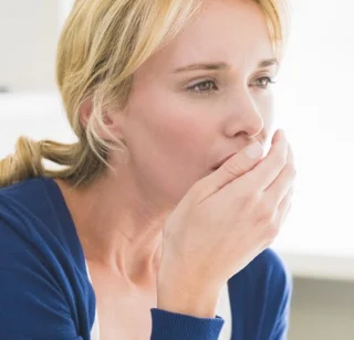 Woman testing to see if she has halitosis (bad breath)