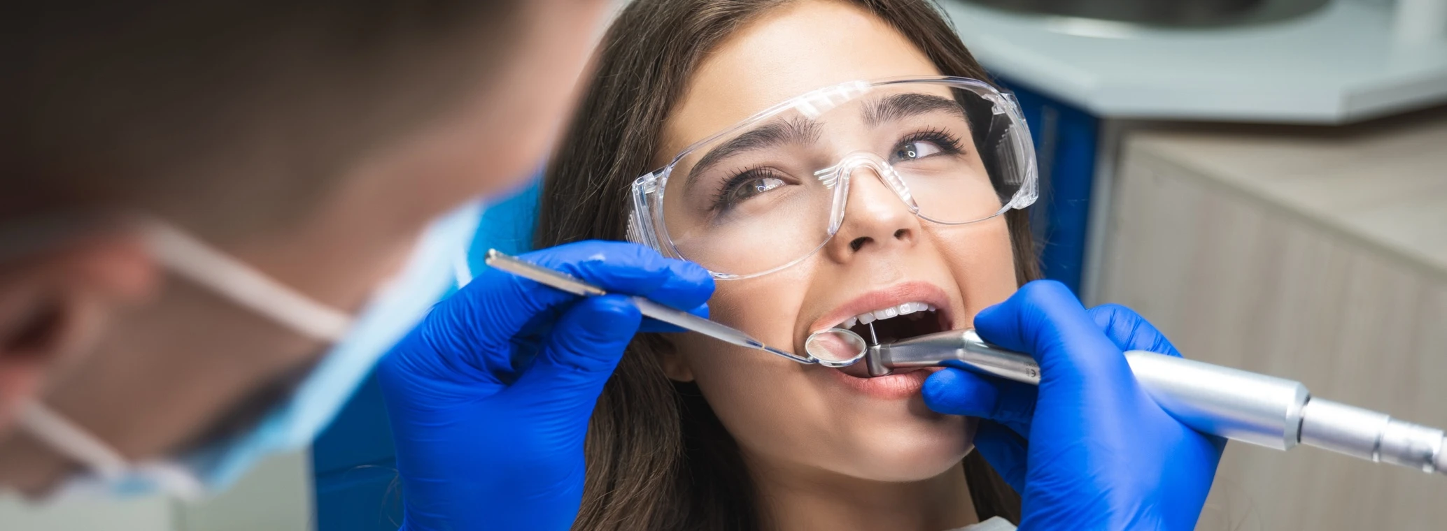 Dentist in mask filling the female patient's root canal.