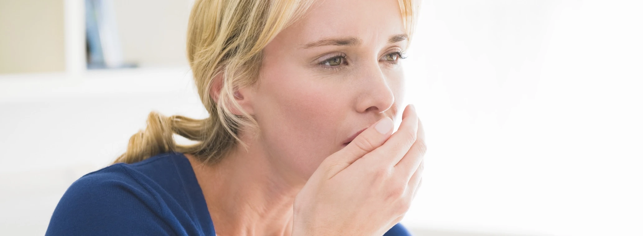 Woman testing to see if she has halitosis (bad breath)