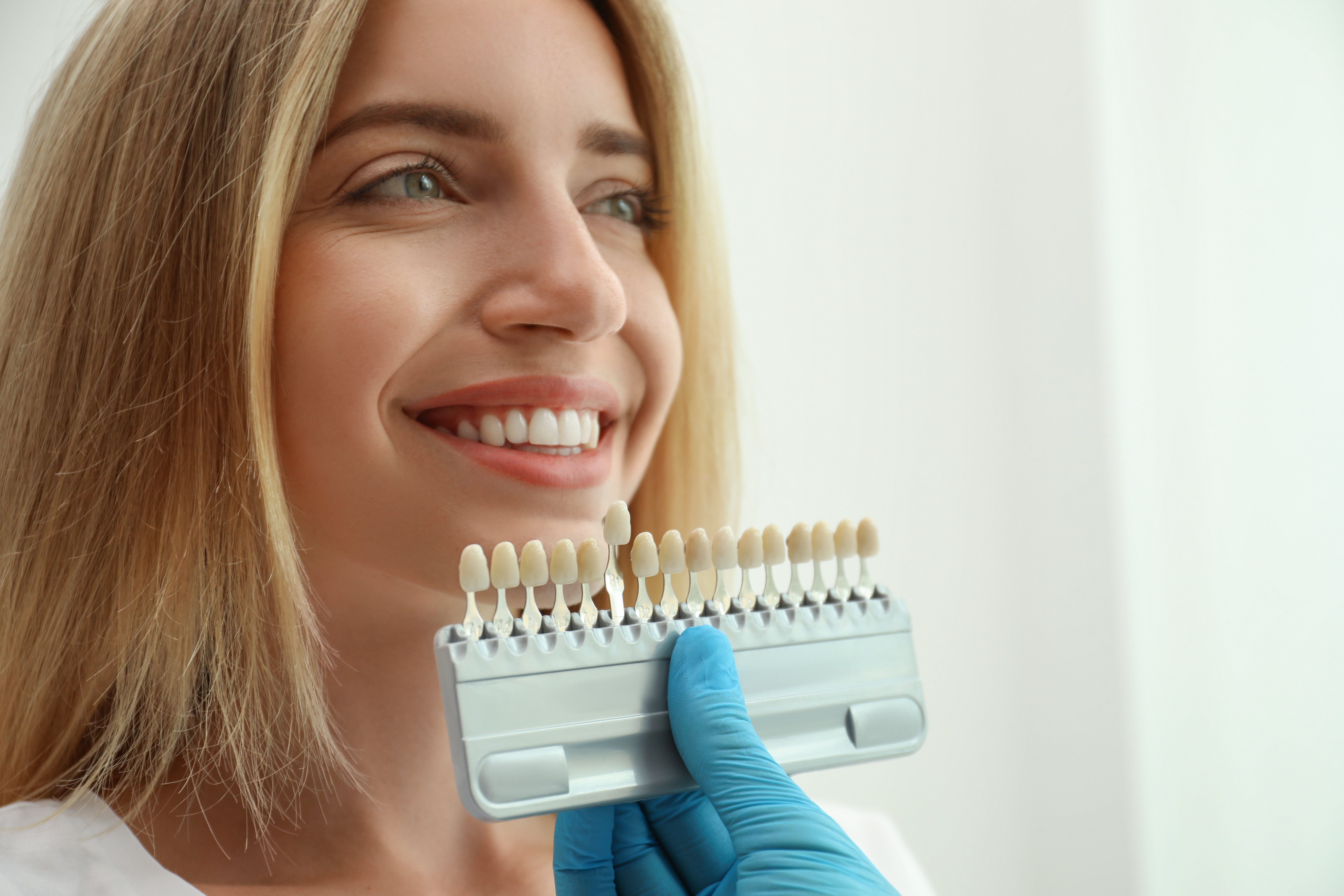 Dentist color-matching the teeth of a female patient 