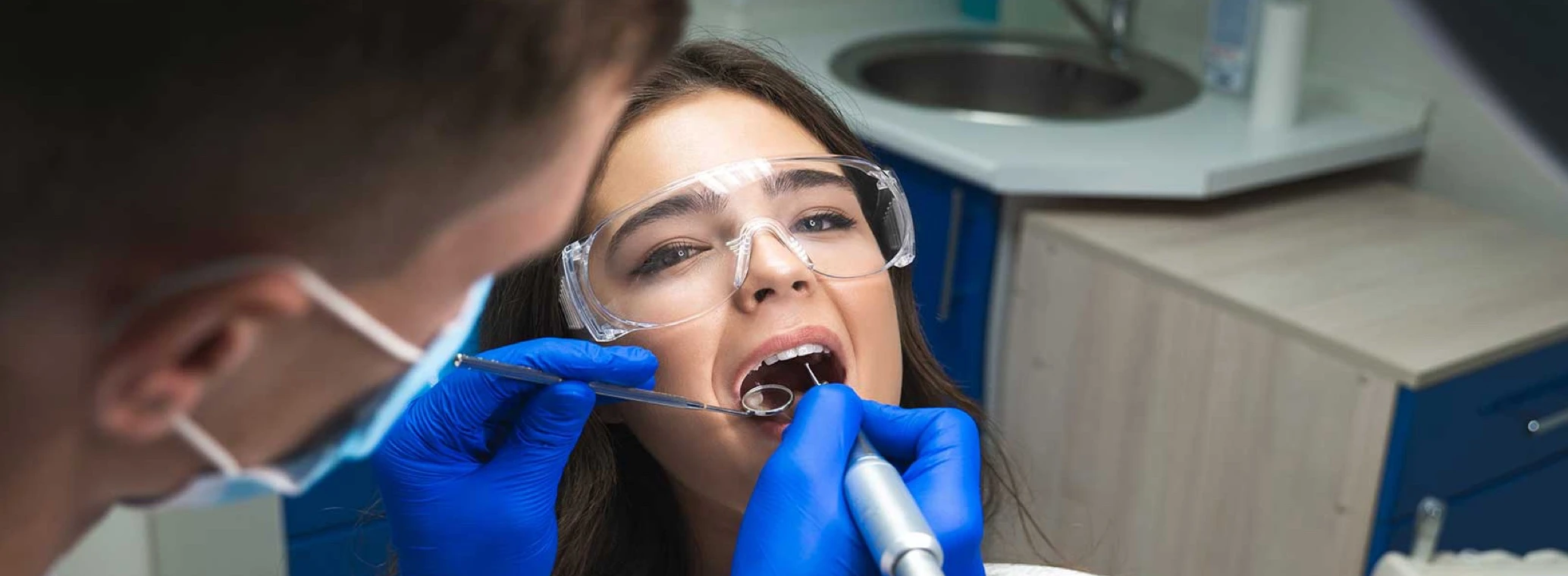 Patient in goggles undergoing a dental procedure in a dentist’s office 