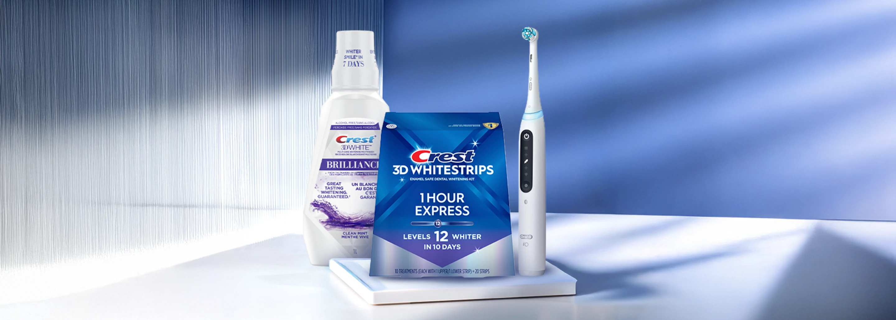 A variety of Crest and Oral-B oral care products lined up, with 3DWhitestrips 1 Hour Express + LED Light on center display.