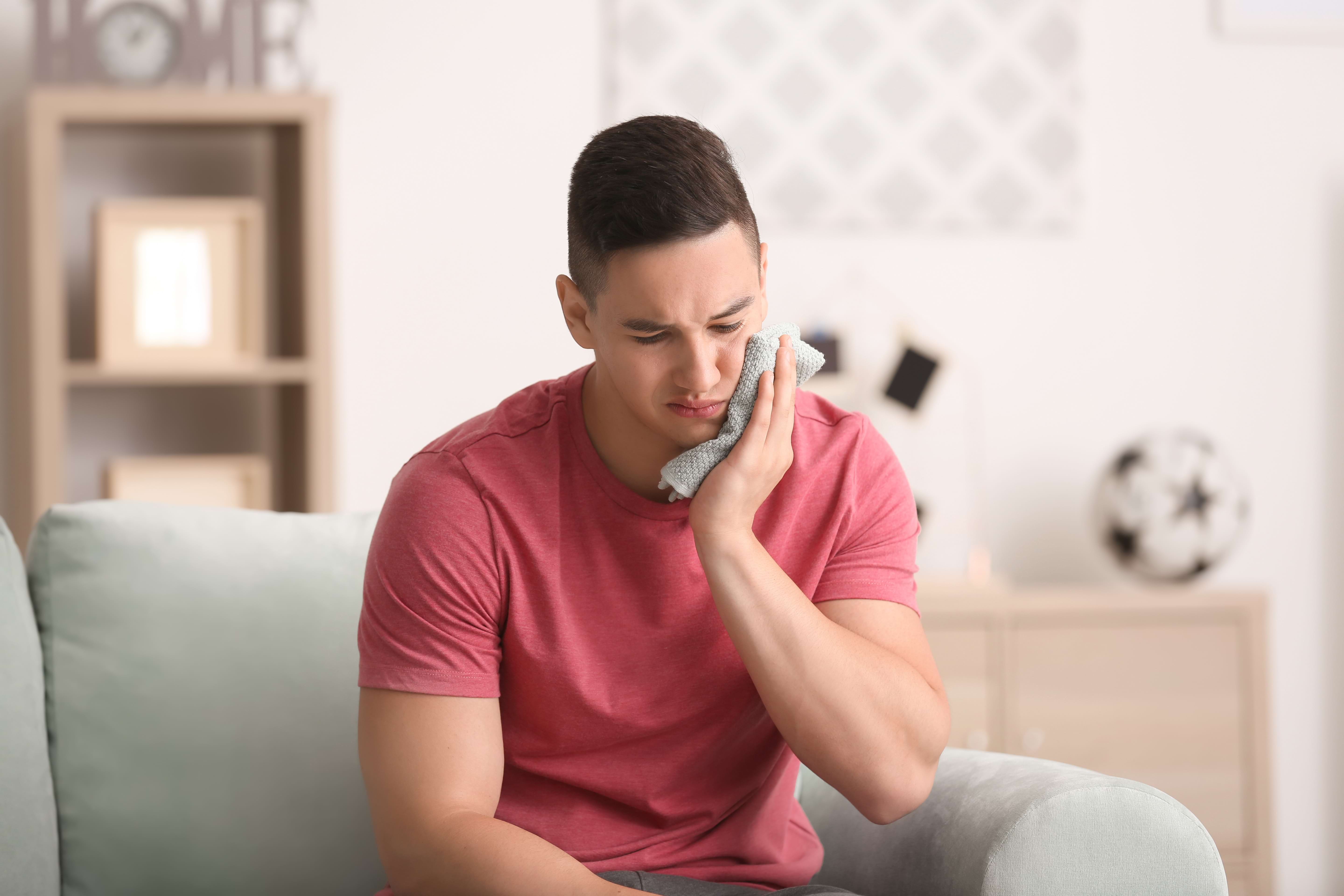 Holding a cold compress to cheek to alleviate pain | Crest 