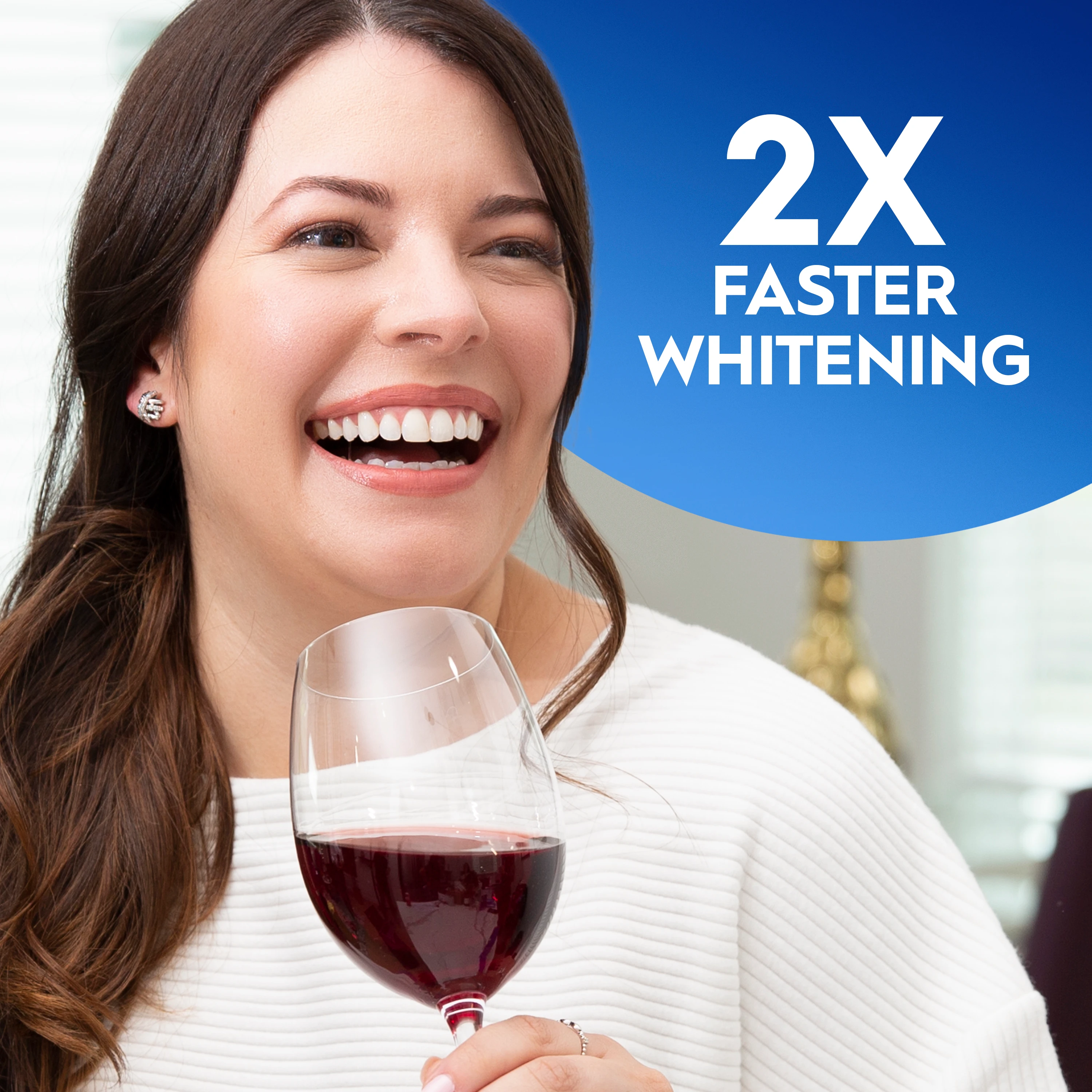 Woman smiling and holding a glass of wine. 2X Faster whitening