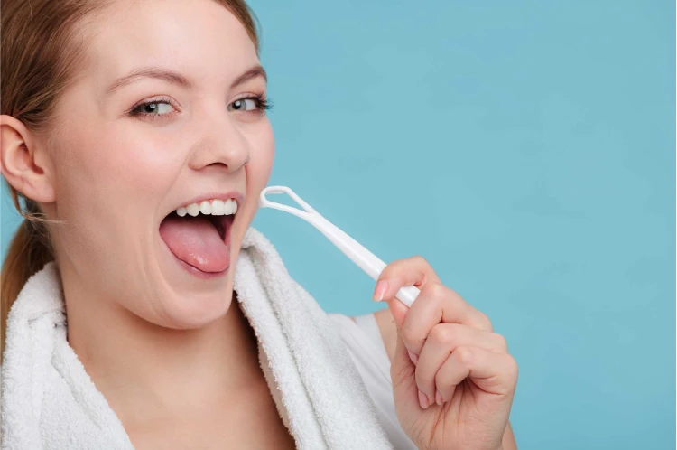 Excited woman sticking out her tongue and holding up her tongue scraper 