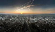 Zonsondergang boven Leerdam, met veel vliegtuigstrepen in de lucht - John Oomen