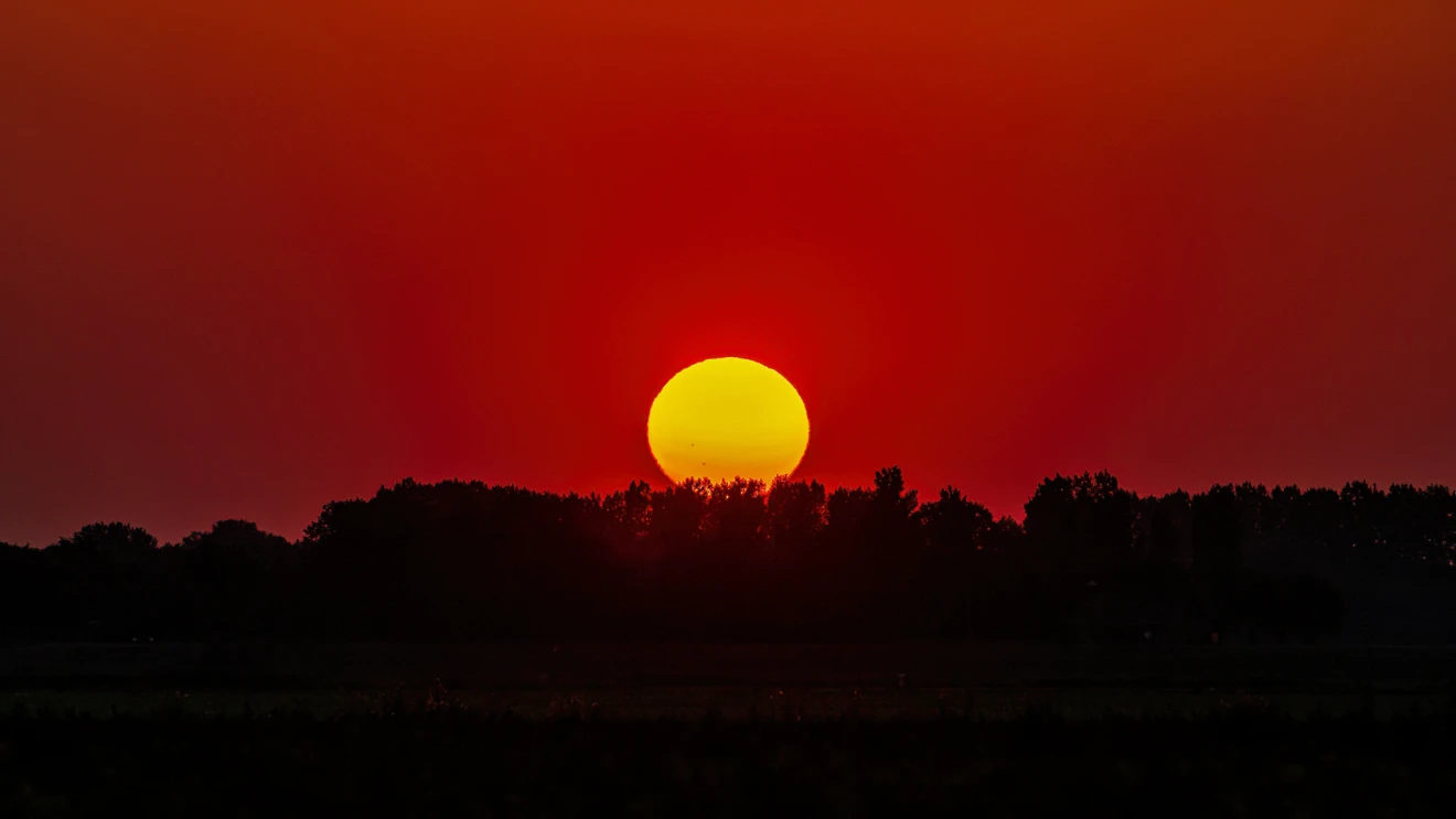 Een rood ondergaande zon, met daarop ook zonnevlekken zichtbaar - Simone Genna