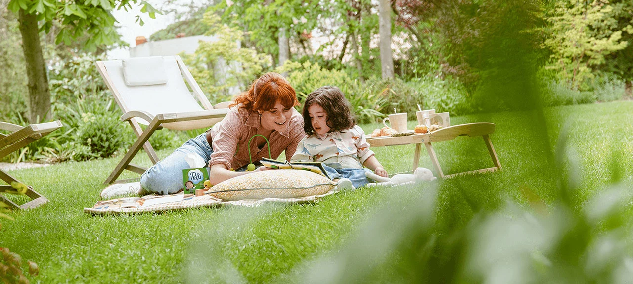 Mãe e filha sentadas no chão do jardim