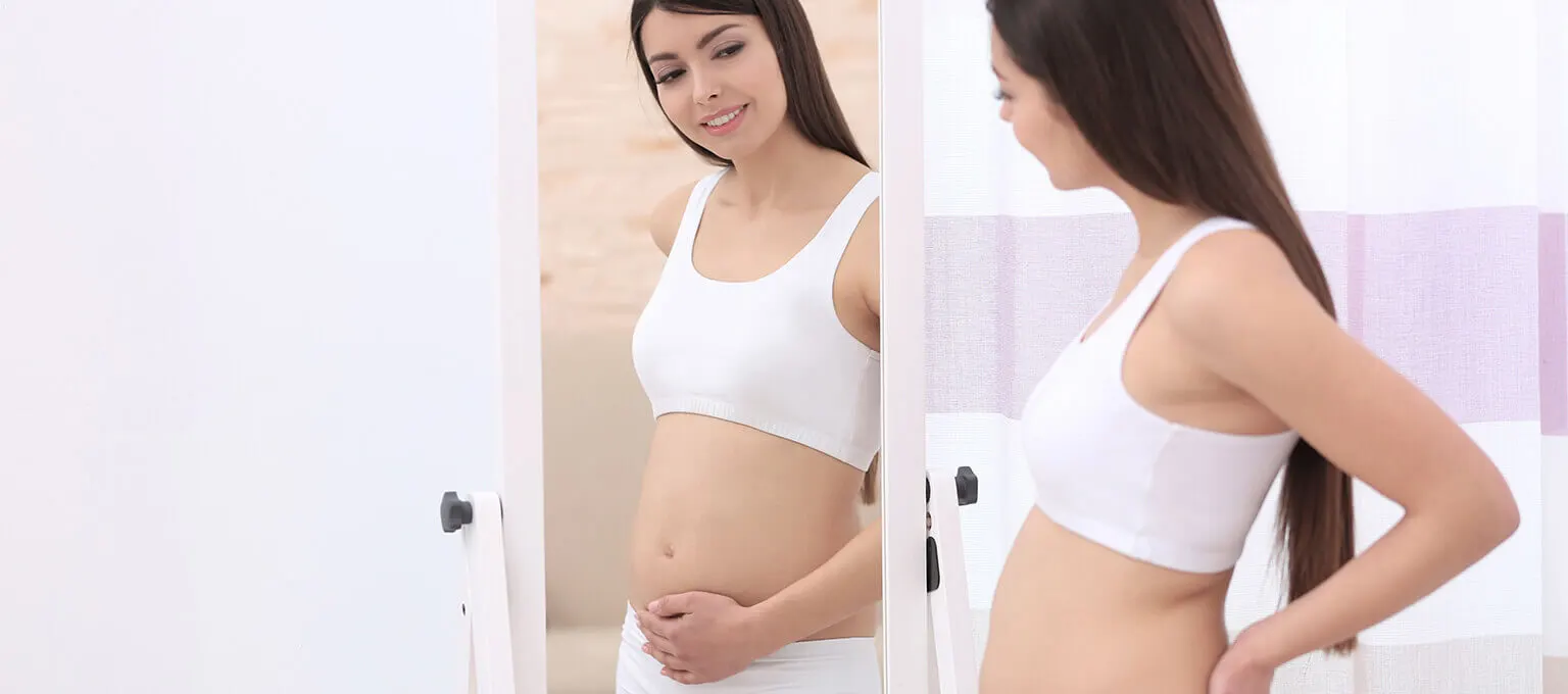Femme enceinte regardant dans le miroirú
