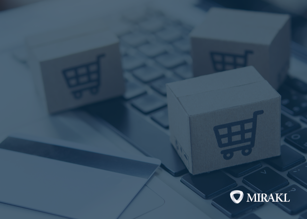 A close-up shot of three small cardboard boxes with printed shopping cart icons, arranged on a laptop keyboard. A credit card is partially visible in the bottom left. The Mirakl logo is in the bottom right corner, suggesting an eCommerce, marketplace or dropship context.