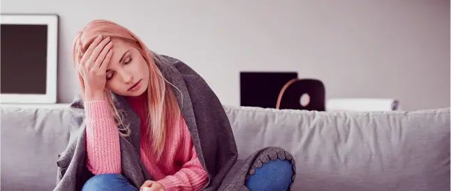 Mujer con gripa sentada en el sofa