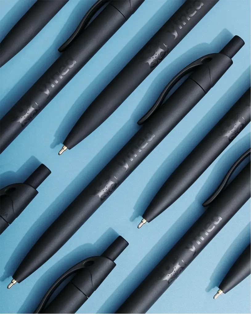 Multiple matte black YFNED pens laid diagonally on a bright blue background.