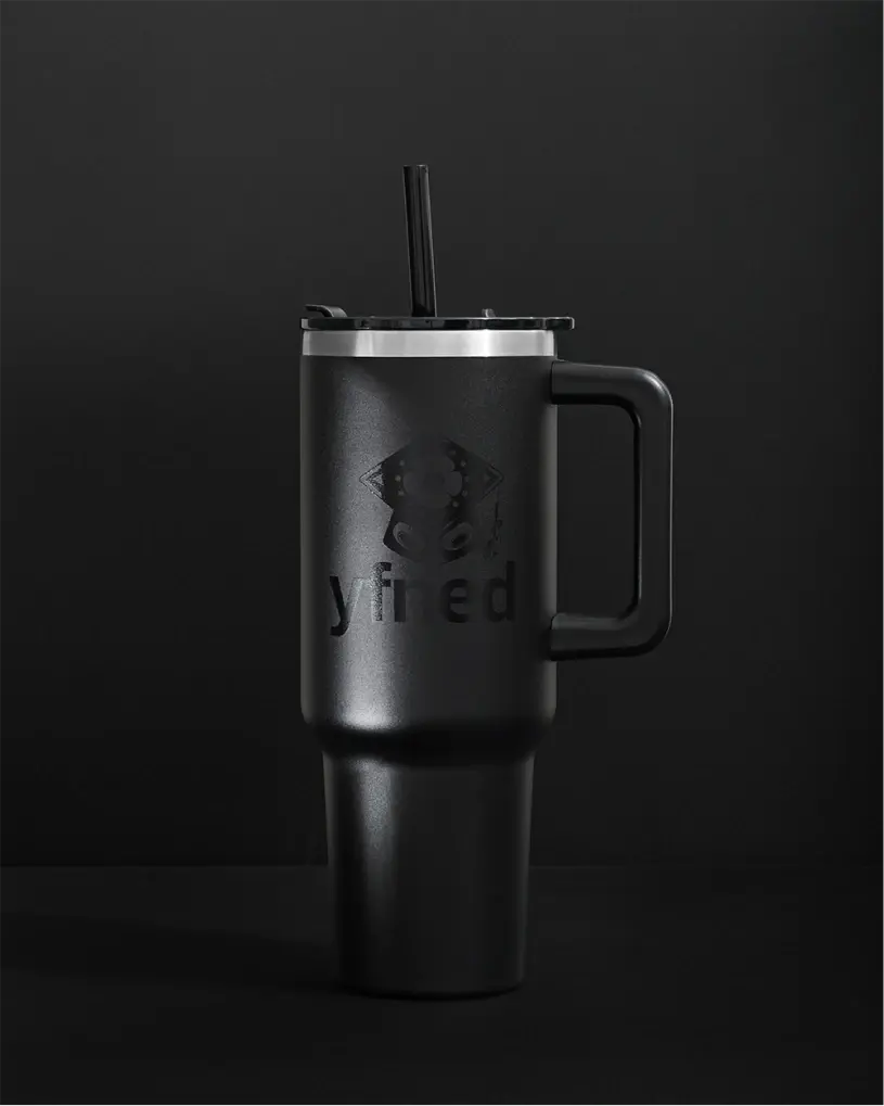 Matte black travel mug with handle and straw, embossed with YFNED logo, on a black background.