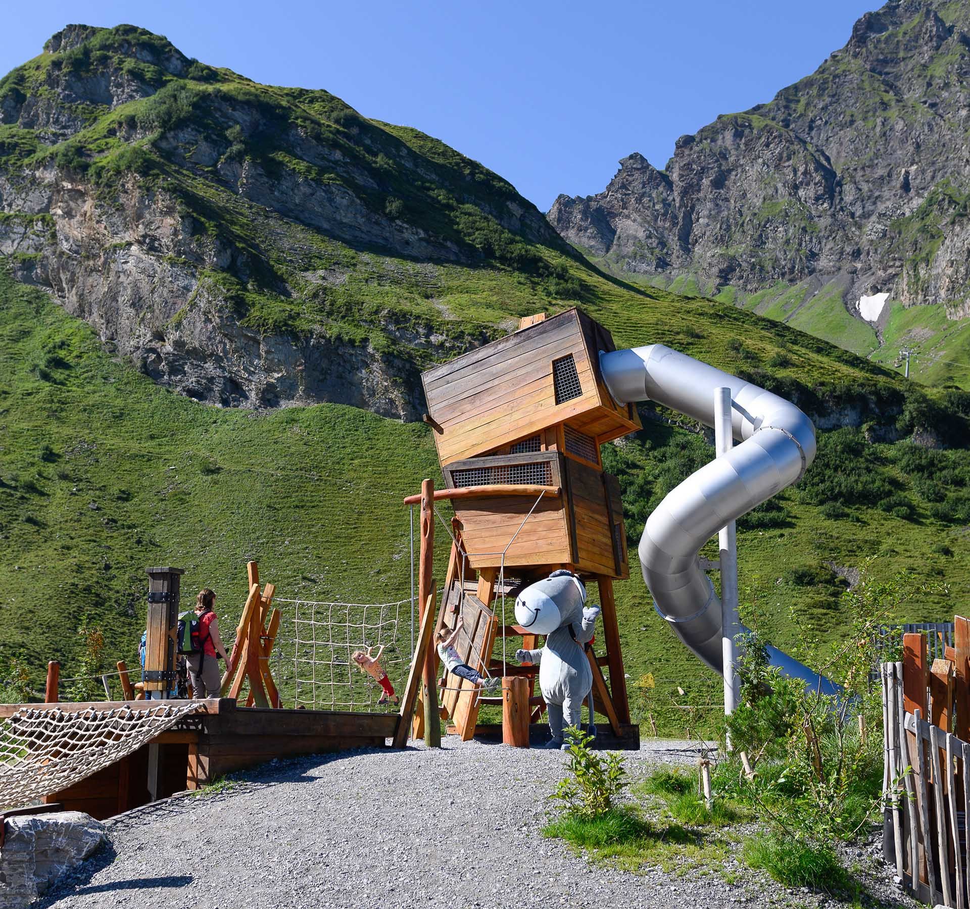 Vue sur l'aire de jeux des contrebandiers à Engelberg-Trübsee avec toboggan, obstacles d'escalade et bien plus encore. Le tout accompagné d'un superbe panorama de montagne.