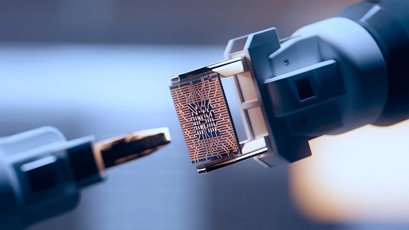 Close-up of robotic arms handling a microchip with intricate circuitry, representing advanced manufacturing or AI technology.