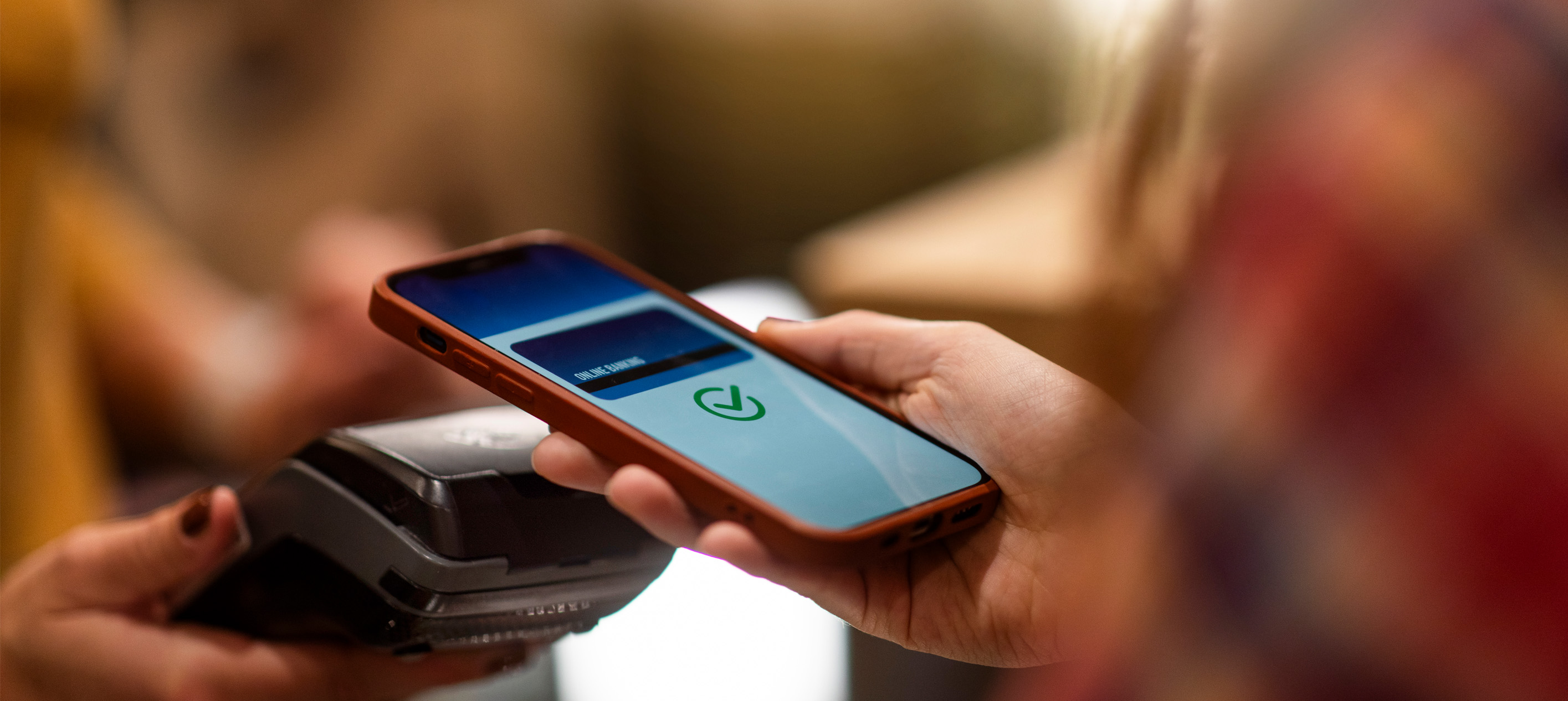person using a smartphone to make a contactless payment at a point-of-sale terminal