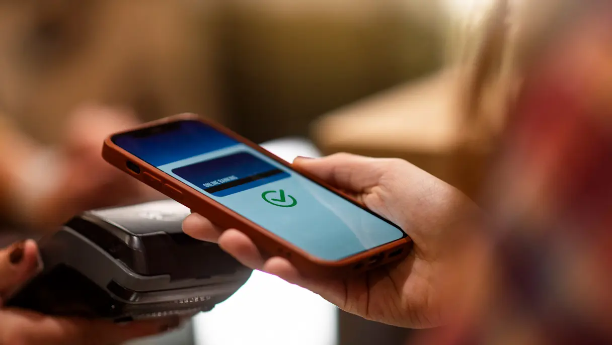 person using a smartphone to make a contactless payment at a point-of-sale terminal