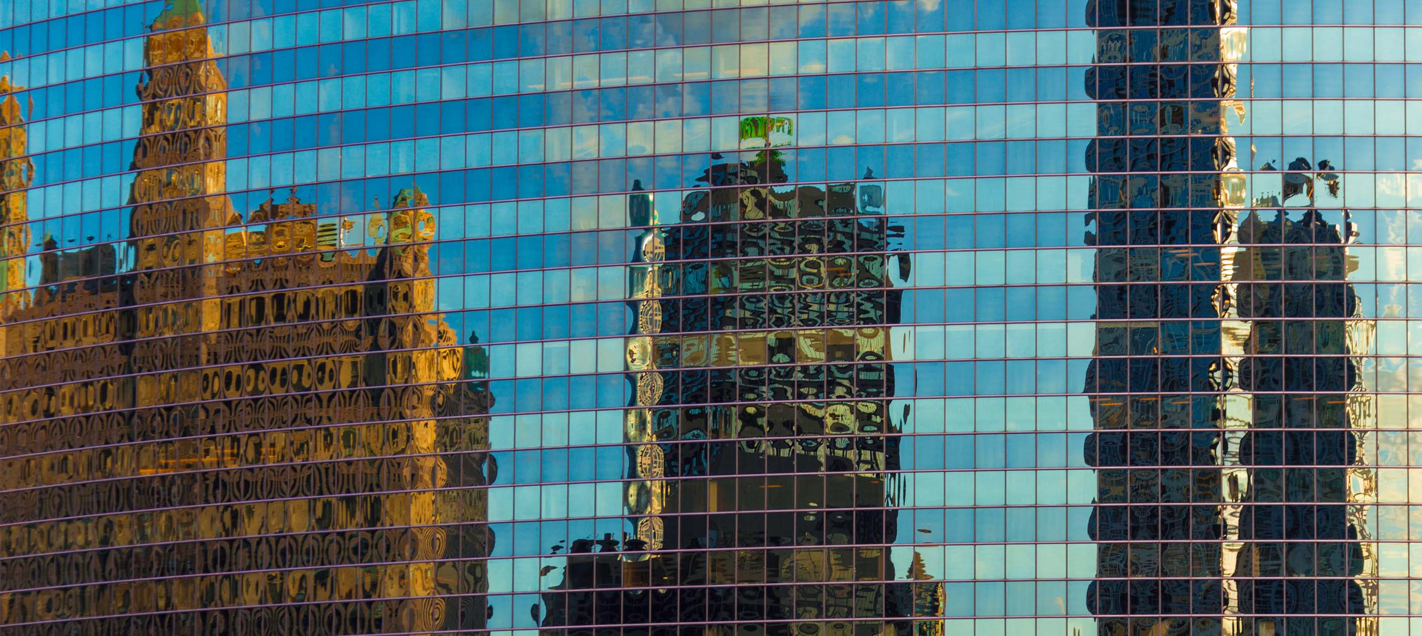 Abstract image of city buildings reflected in the windows of an office building.