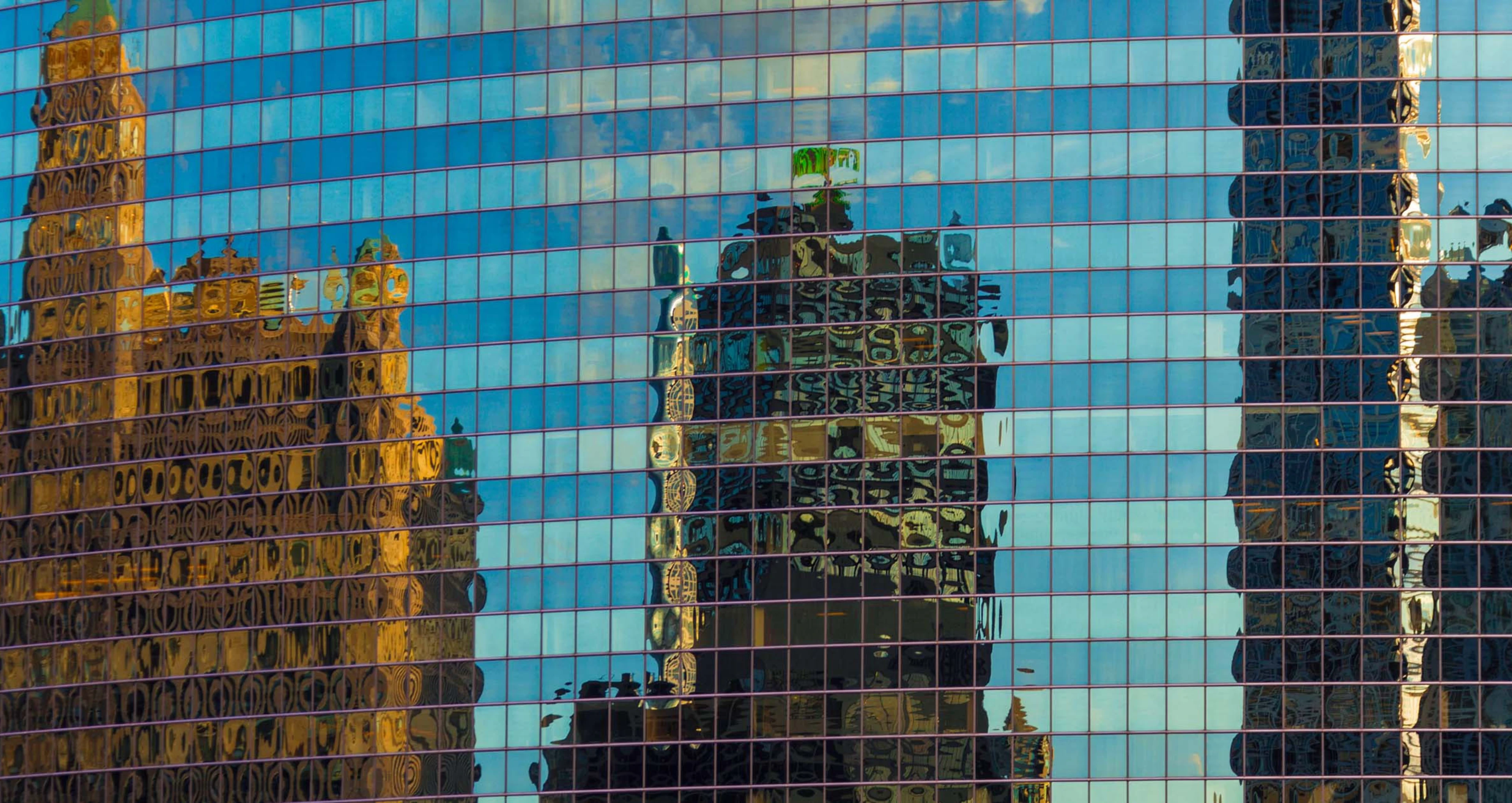 Abstract image of city buildings reflected in the windows of an office building.