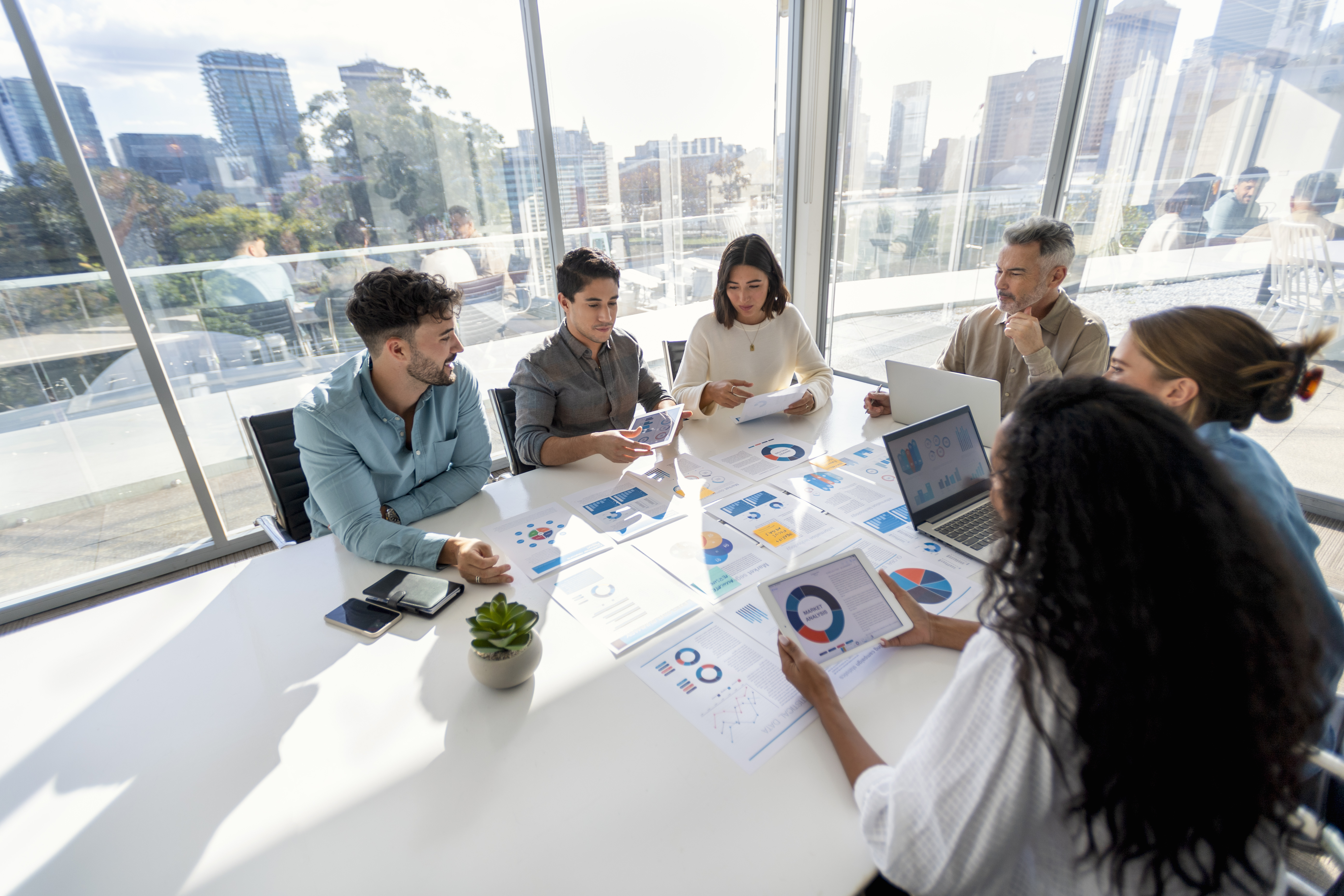 Diverse business team reviewing financial charts and reports at a conference table with city views.