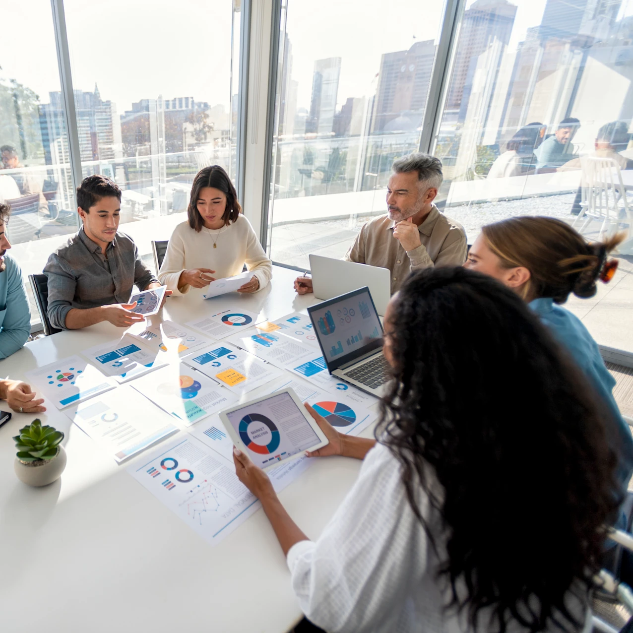 Diverse business team reviewing financial charts and reports at a conference table with city views.
