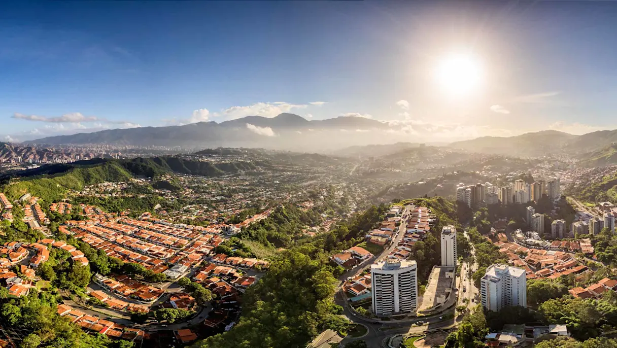 Aerial panoramic view of Caracas, Venezuela, with residential areas, green hills and mountains.