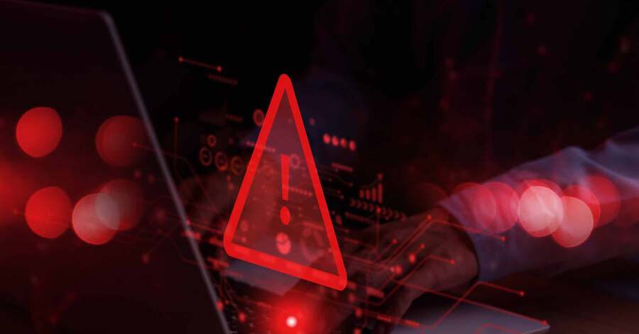 Cyber warning symbol over person typing on laptop.