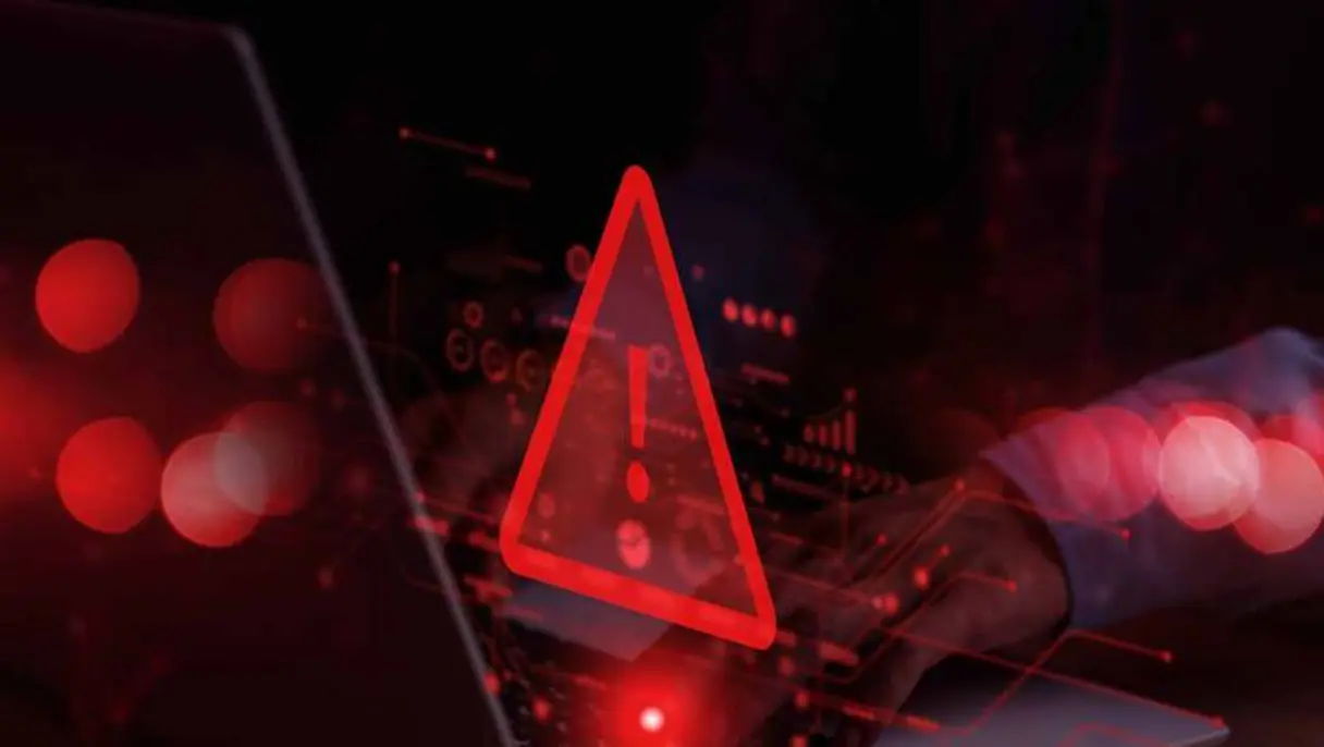 Cyber warning symbol over person typing on laptop.