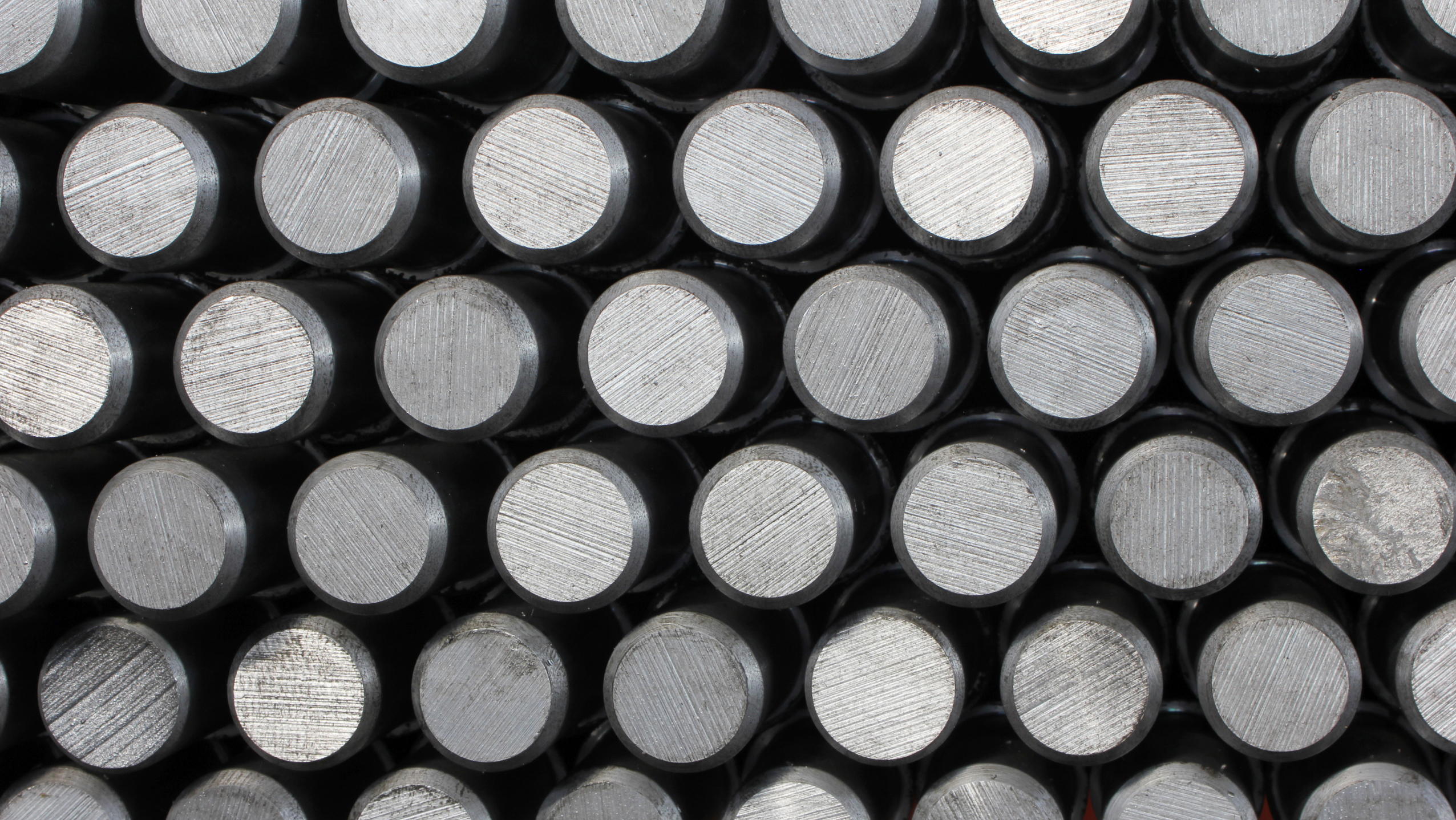 Close-up view of stacked steel rods with a polished surface, showcasing their uniform cylindrical shape and texture.