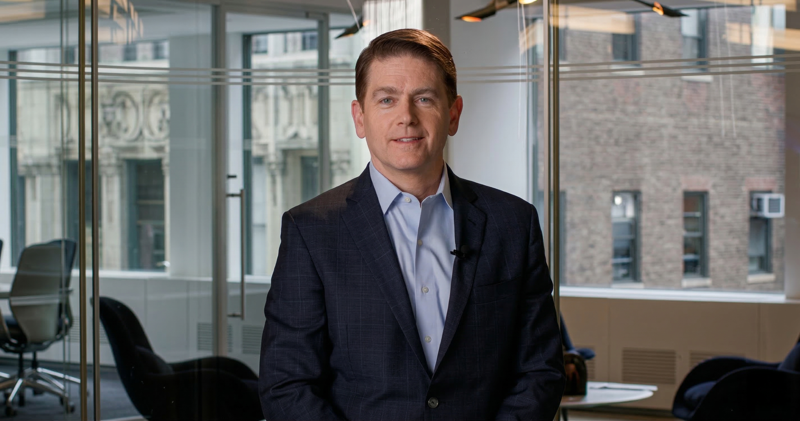 Mike Driscoll in a modern office with glass walls and blurred furniture in the background.