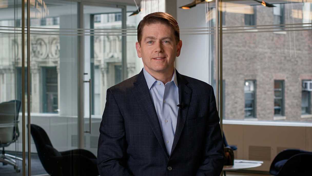 Mike Driscoll in a modern office with glass walls and blurred furniture in the background.