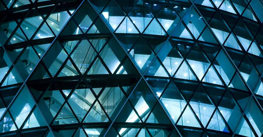 Geometric glass facade lit at night.