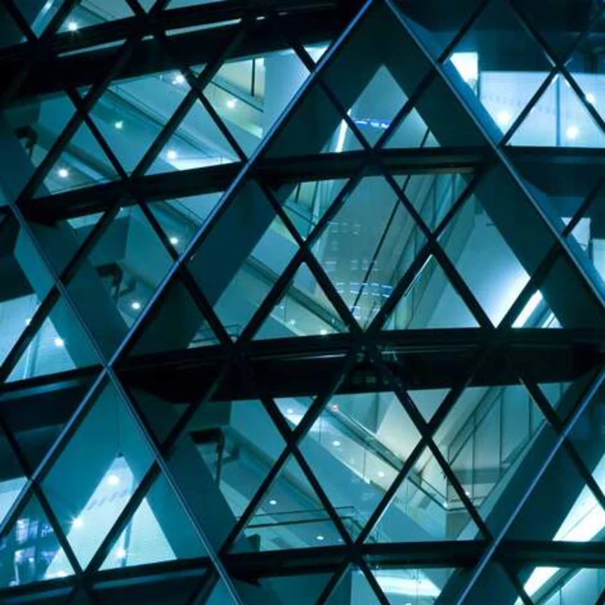 Geometric glass facade lit at night.