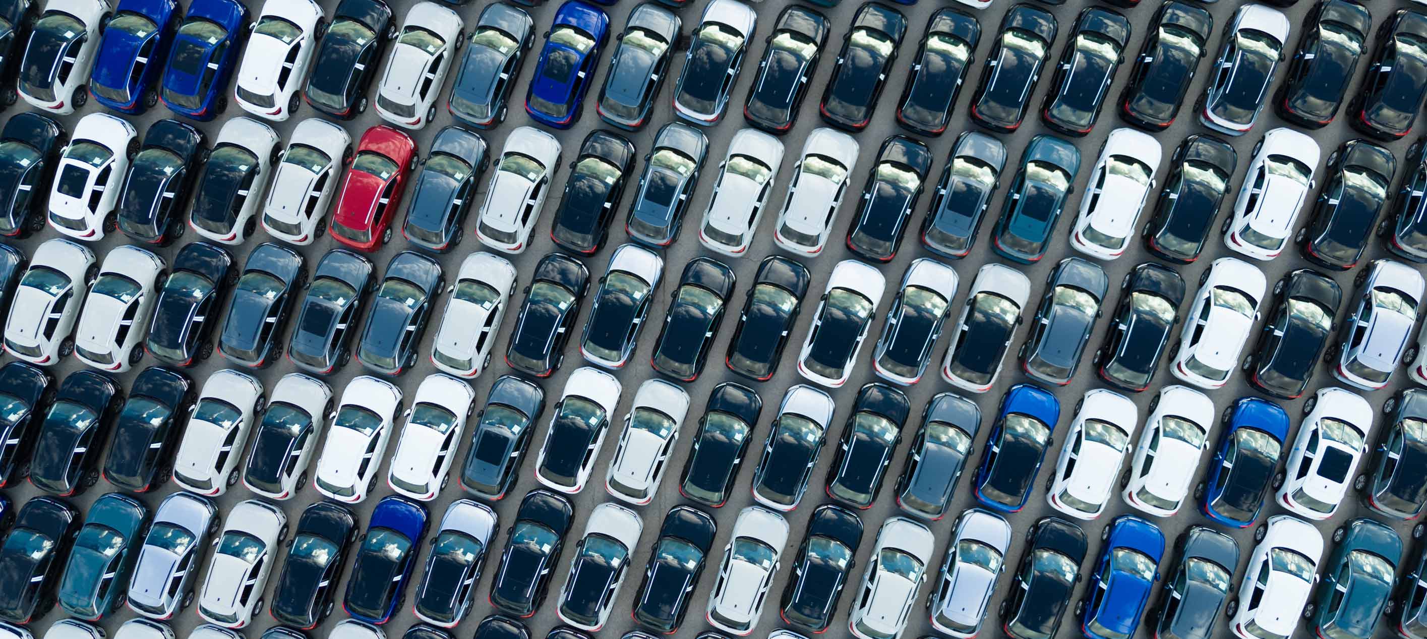 Aerial view of rows of parked new cars in various colors.