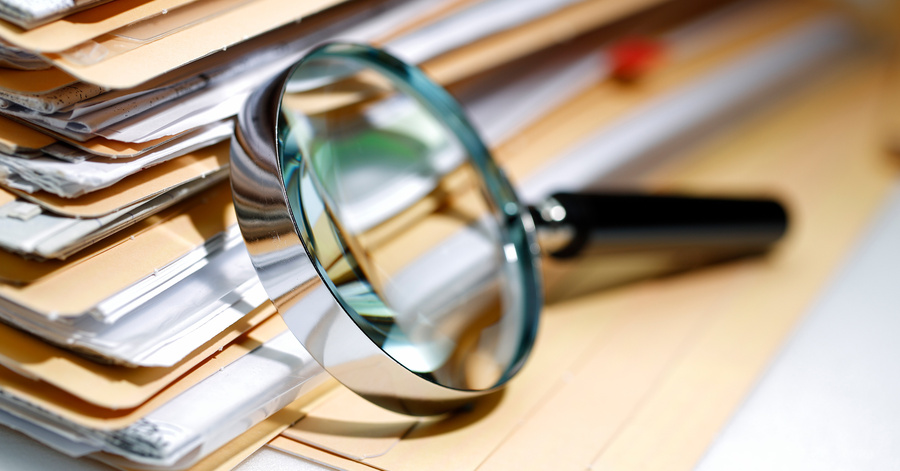 A magnifying glass on a stack of files